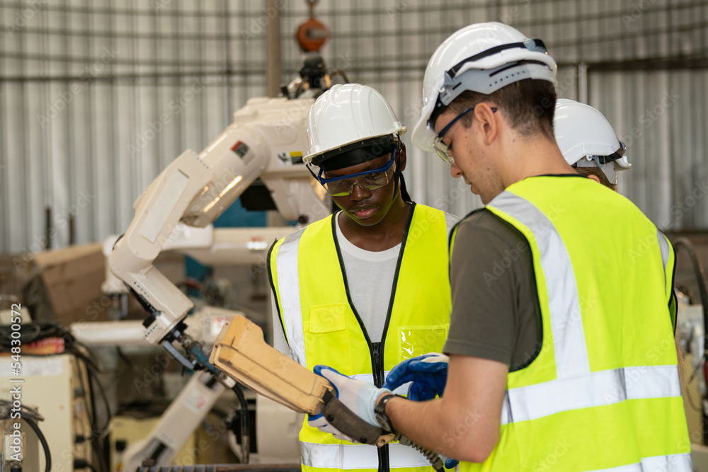 Robotics engineer working on maintenance of modern robotic arm in factory warehouse Robotics engineer working on maintenance of modern robotic arm in factory warehouse