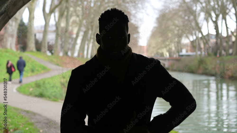 Silhouette of young black man walking under bridge during cold winter season Silhouette of young black man walking under bridge during cold winter season