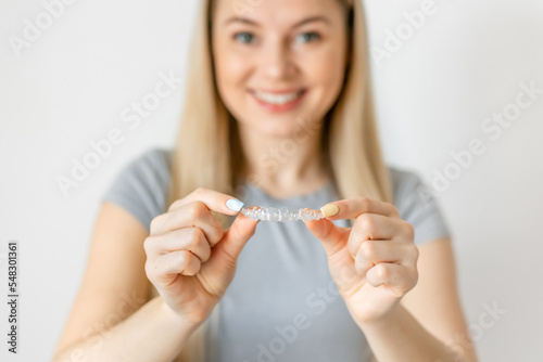 Smiling woman holding Invisalign braces in studio, dental healthcare and Orthodontic concept