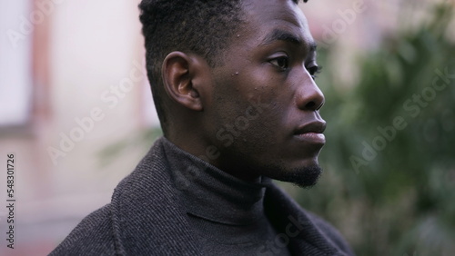 Serious young black man standing outdoors. Stoic handsome African person