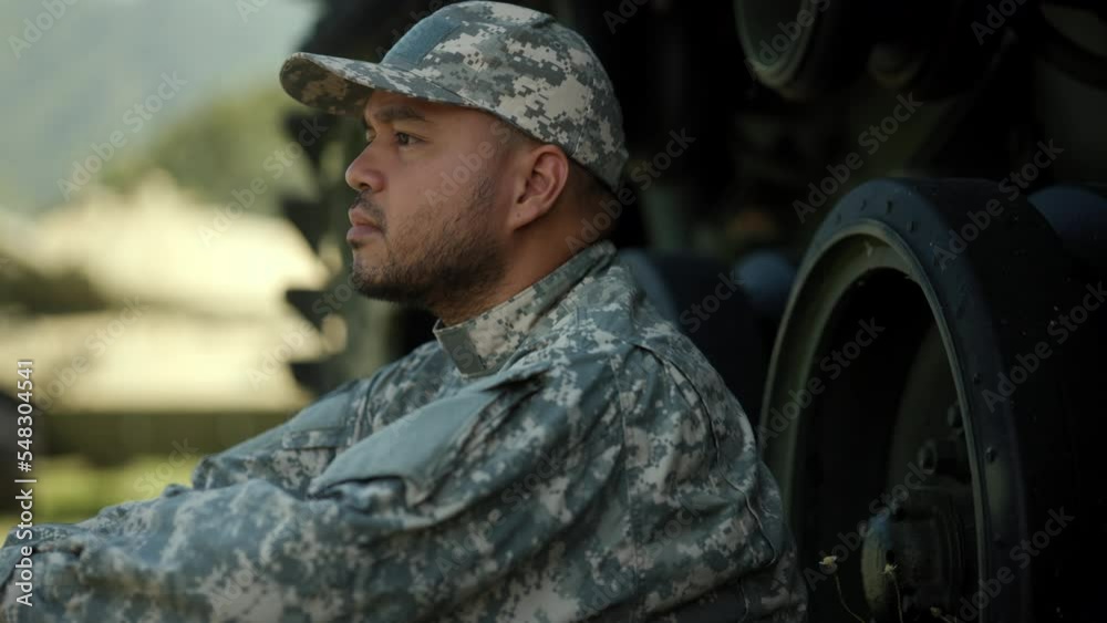 Commander Army soldier military defender of nation in uniform siting near battle tank while state of war. Serious man in military uniform special forces soldier standing against on field Mission.