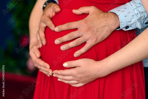 Guy and pregnant girl hold hands on their belly