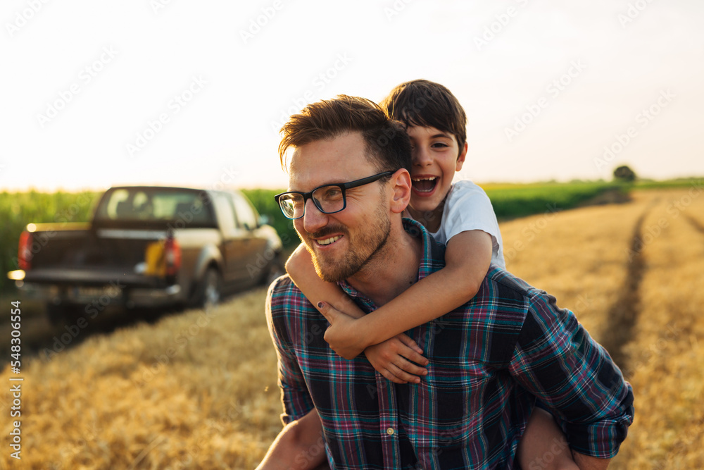 Naklejka premium Father caries his son on his back in the field