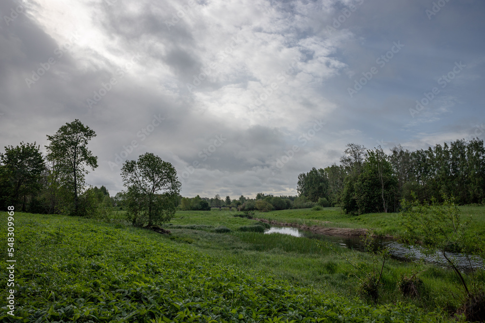 Svēte river runs through meadow near Jelgava town, Latvia, beautiful cloudscape