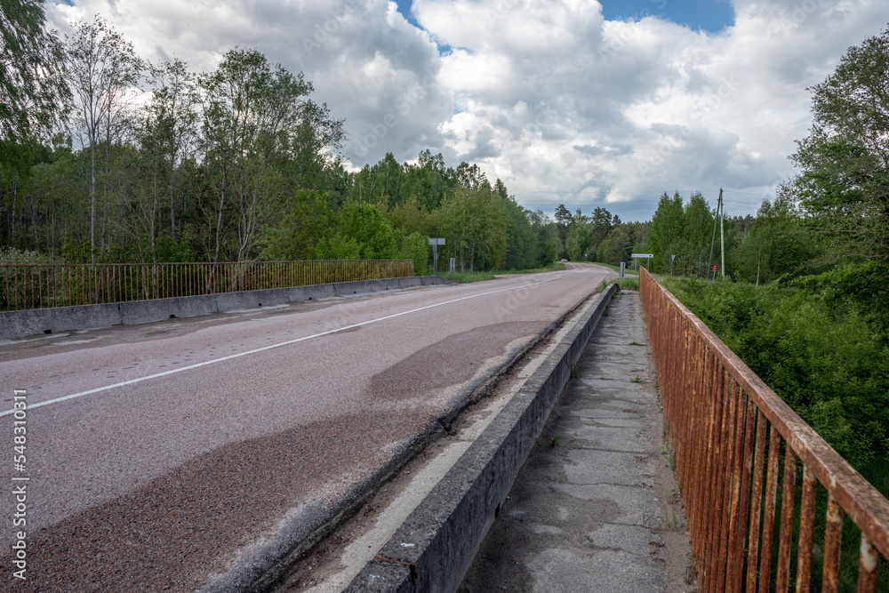 concrete bridge with metal iron railing over river Iecava near Garoza village, Latvia. Perspective view of road and bridge concrete bridge with metal iron railing over river Iecava near Garoza village, Latvia. Perspective view of road and bridge