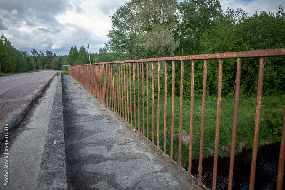 concrete bridge with metal iron railing over river Iecava near Garoza village, Latvia. Perspective view of road and bridge
