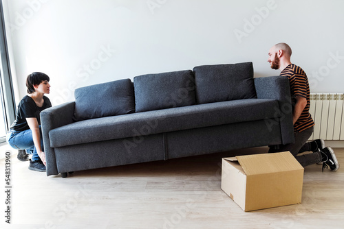 Foto Una pareja joven levantando un sofá para moverlo