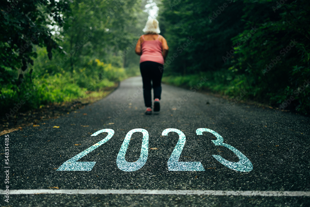 Numbers 2023 written on the road towards new goals in 2023 and female