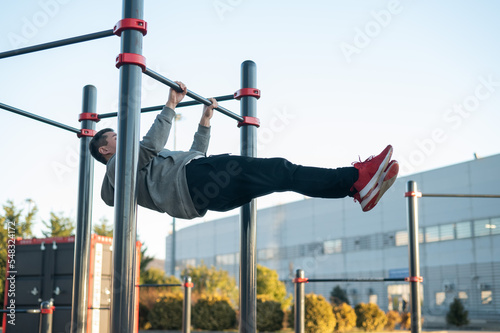 Young caucasian man doing parallel bars exercise outdoors. 