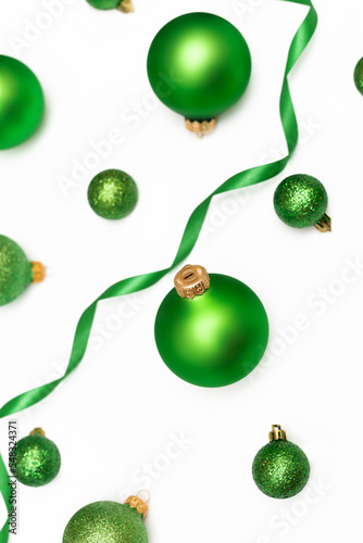 Christmas flatlay composition of green balls and ribbon on the white background