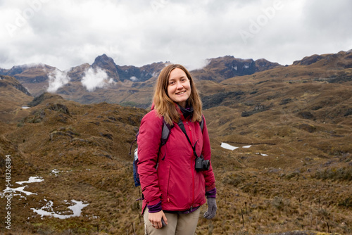A landscape with a smiley female hiker looking at camera in the Cajas National Park in the highlands of Ecuador, tropical Andes.