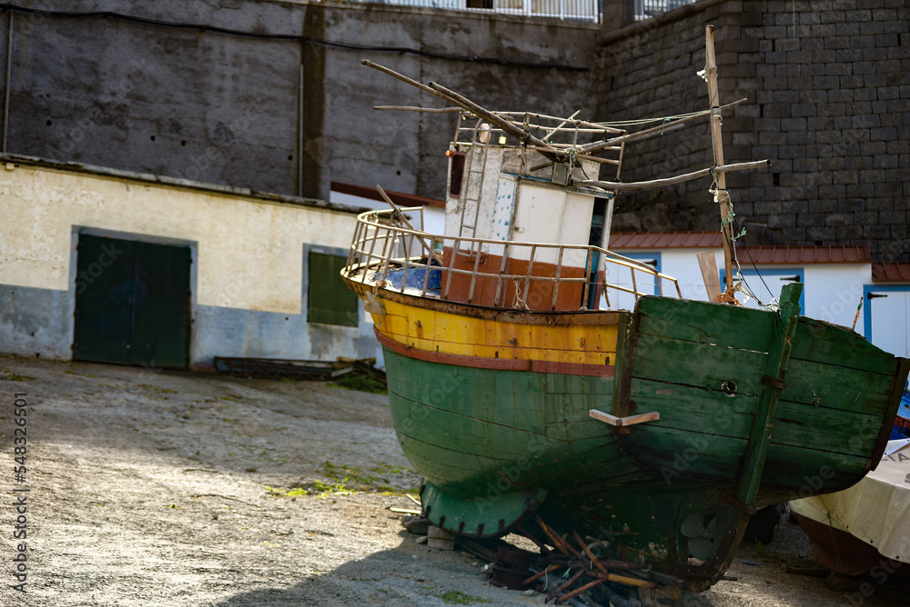 Lonely wooden fishing boat. Located on the beach awaiting renovation. Vintage. An old boat with a motor.