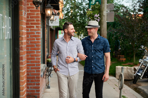 Same sex male couple walking down street arm in arm.