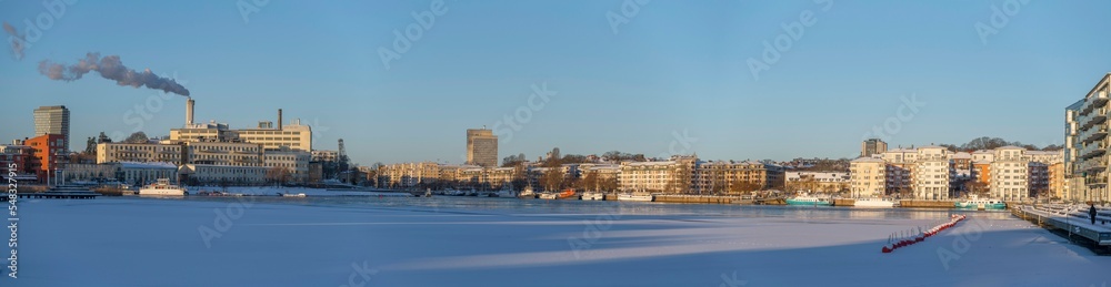 Panorama, snowy winter view at the bay Hammarby Sjö, low solstice, long shadows and clear sky, in Stockholm