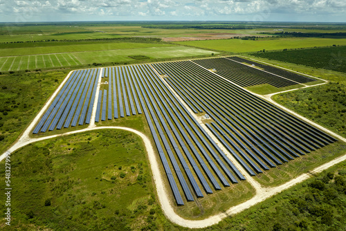 Aerial view of sustainable electrical power plant between agricultural farmlands with photovoltaic panels for producing clean electric energy. Concept of renewable electricity with zero emission