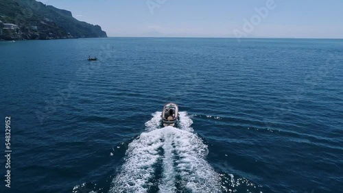 Aerial view of a boat on the Amalfi Coast, Italy. Drone slow motion footage with smooth camera movement. Sea waves diverge from the movement of the yacht on a sunny day