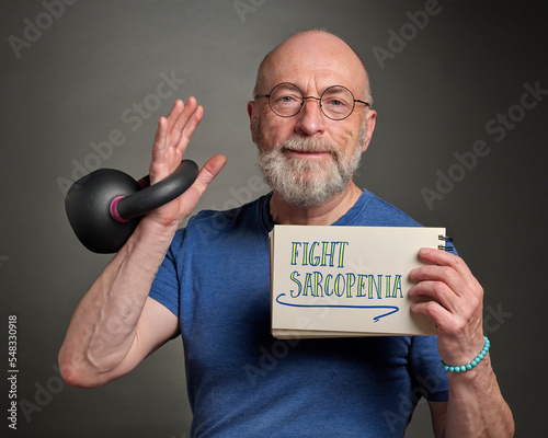 fight sarcopenia, muscle loss due to aging - inspirational message in a notebook held by a senior man (in late 60s) exercising with iron kettlebell, active senior and fitness concept photo