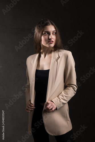 Portrait of a young brunette with long hair in the studio. Dramatic photo in dark colors.