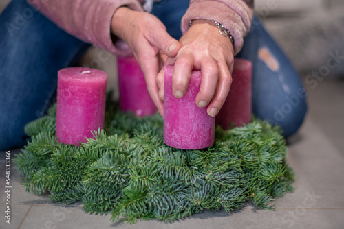 Hände einer Frau, die einen Adventskranz zu Weihnachten dekorieren photo