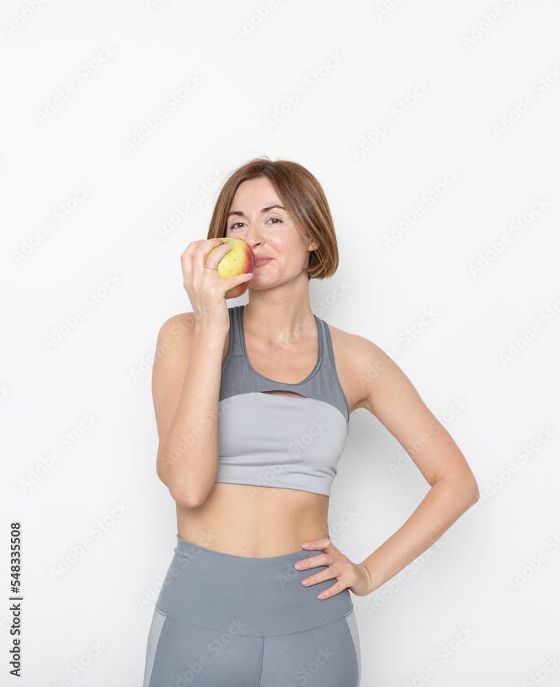 Close up portrait of pretty woman in sportswear holding apple isolated on white background. Healthy lifestyle concept Close up portrait of pretty woman in sportswear holding apple isolated on white background. Healthy lifestyle concept