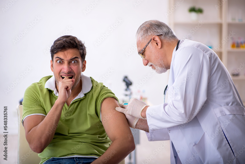 Fototapeta premium Young male patient visiting old male doctor in vaccination conce