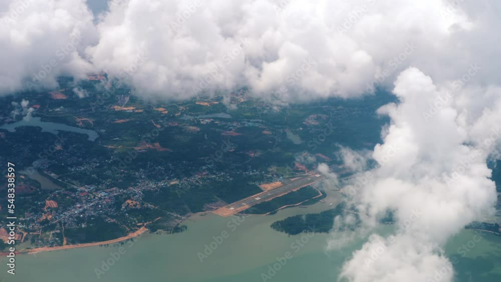 Fly over white fluffy clouds. View from the porthole to the area and the sea. Tourism and travel concept Fly over white fluffy clouds. View from the porthole to the area and the sea. Tourism and travel concept