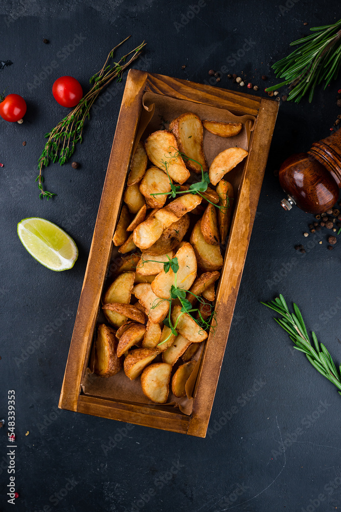 Baked rustic potato wedges with salt on a wooden board.