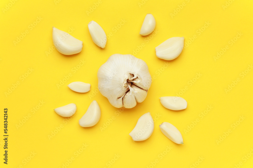 Fresh white unpeeled head bulb of garlic and garlic cloves on yellow
