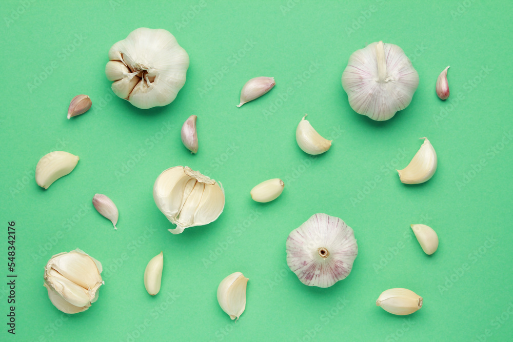 Fresh white unpeeled head bulb of garlic and garlic cloves on green color background. Vegan, organic, vitamins. Natural antibiotic, antioxidant, Allicin. Top view. Flat lay
