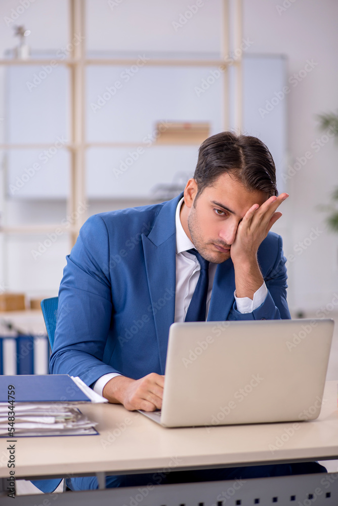 Young male employee and too much work in the office Young male employee and too much work in the office