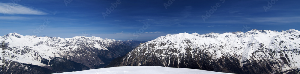 Panorama of high snow-capped mountain peaks and beautiful sky with clouds at sunny day.