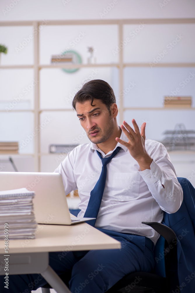 Naklejka premium Young male employee and too much work in the office