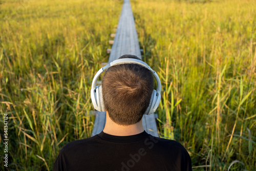 Listening to an audiobook and calm music in nature, a man with headphones looks at the horizon