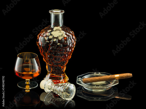 Open decanter with cognac, glass and cigar in a glass ashtray