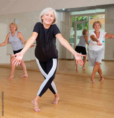 Portrait of a mature dancing woman at a group training session, practicing an energetic swing in a studio of dance