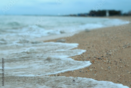 Sea wave rolls along the shore of a sandy beach, autumn footage of the seascape, blurred background, selective focus Sea of Azov, Russia