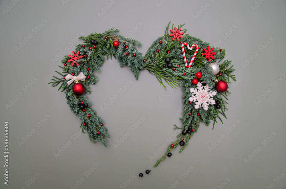 Christmas composition. Heart symbol made of pine, cypress, thuja branches branches, balls, berries and wood decorations. Christmas, winter, new year concept. Flat lay, top view, copy space