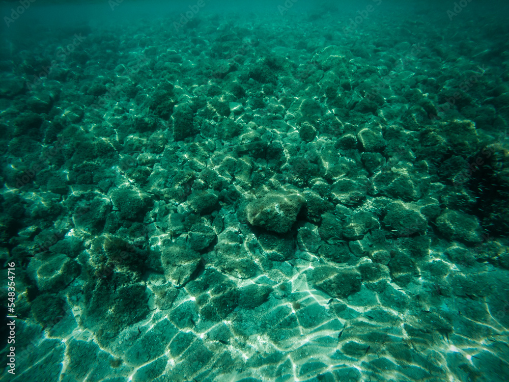 Underwater picture of stone sea bottom with waves refraction visible on the sea floor
