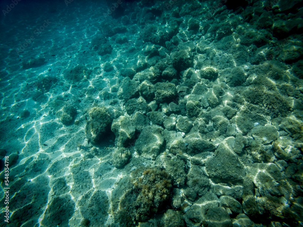 Underwater picture of stone sea bottom with waves refraction visible on the sea floor