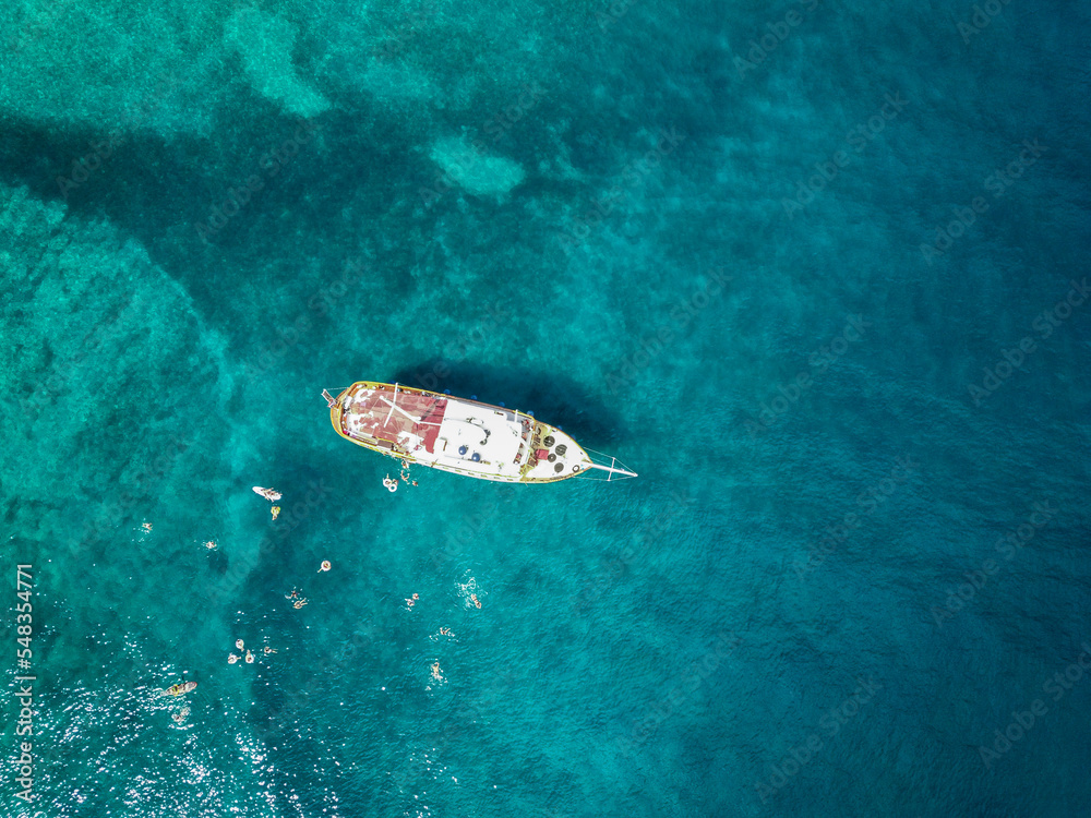 Aerial top down view of tourist ship anchored in the amazing, turquoise shallows of Brac island, Croatia with people swimming in the water Aerial top down view of tourist ship anchored in the amazing, turquoise shallows of Brac island, Croatia with people swimming in the water