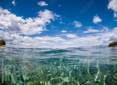 Amazing, crystal clear sea at Brac island, Croatia, with visible underwater bottom full of stones and wonderful, blue sky reflected in the water