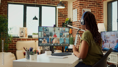 Female freelancer attending business meeting on videocall with webcam, using computer to talk to people on online teleconference call. Young adult chatting on remote videoconference, work from home.
