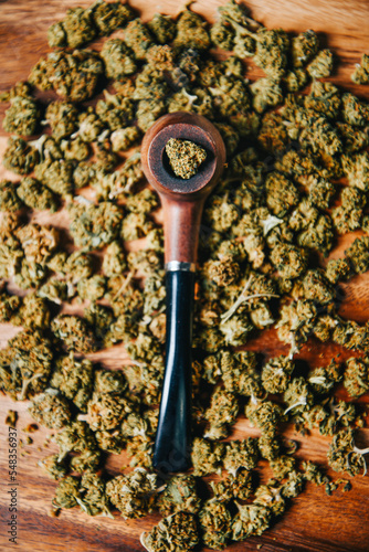 Wooden pipe for smoking marijuana on the table against the background of a buds of cbd sativa or indica tgk. Drugs and medicine. photo