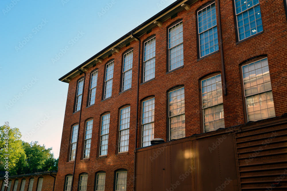 Façade of red brick industrial building, warehouse or inn with a blue sky in the background
