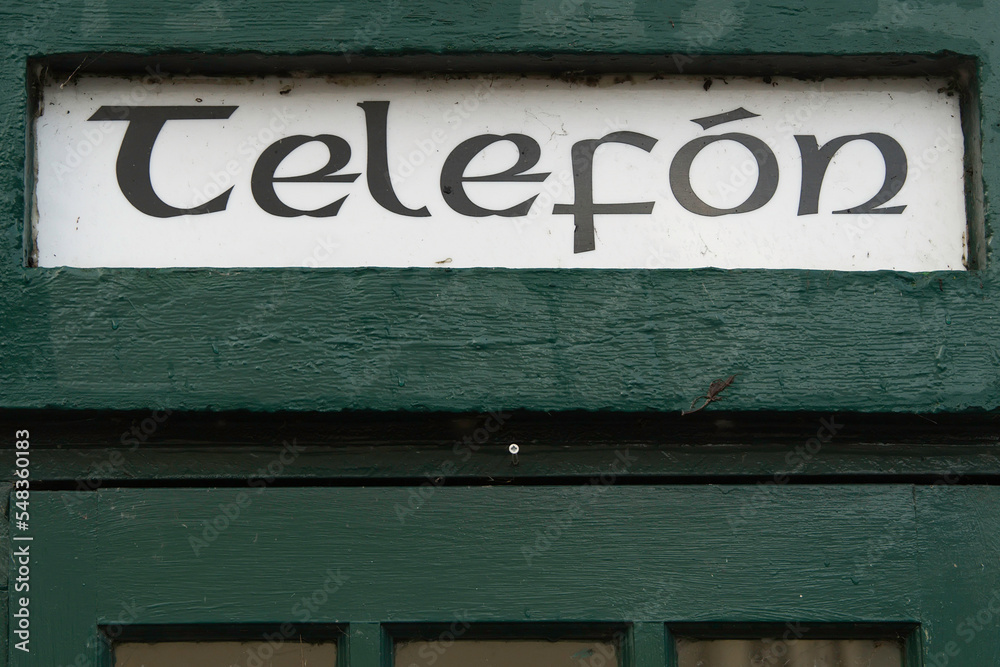 Obraz premium Sign in Irish language phone on an old phone booth.