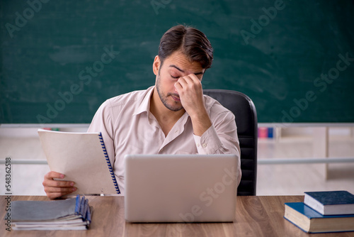 Young male teacher sitting in the classroom