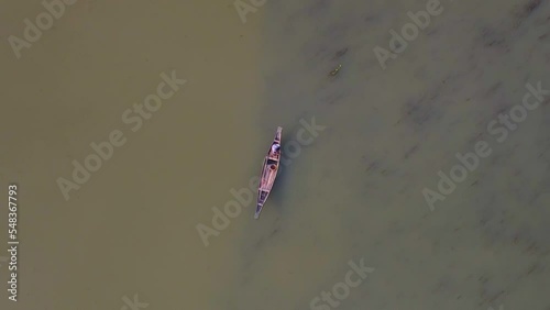 Aerial View Of Lone Fisherman On Traditional Wooden Boat On River. Rotating Shot, Pedestal Down photo