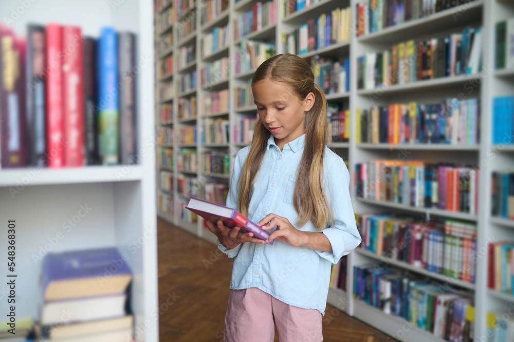 Long-haired cute girl with a big book in hands