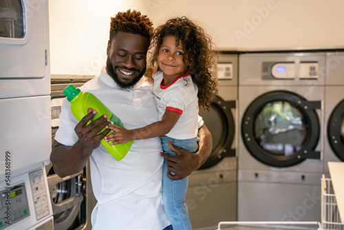 Fotografija Happy young parent and his kid at a public laundromat