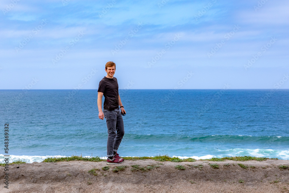 teenage boy enjoys standing at the dune of the beach teenage boy enjoys standing at the dune of the beach